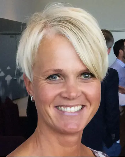 Kvinne med lyst hår smiler til kameraet. Foto.